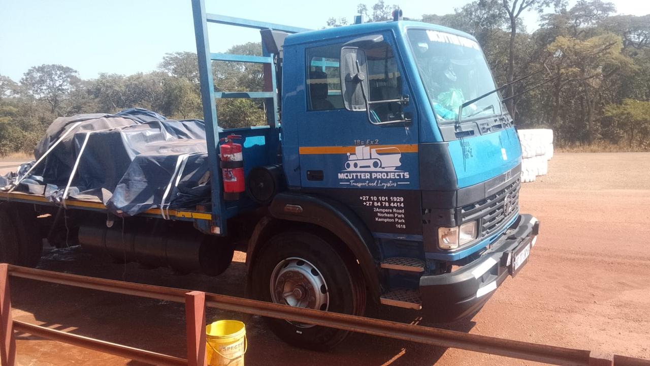 Mcutter worker standing by loaded curtain-side truck